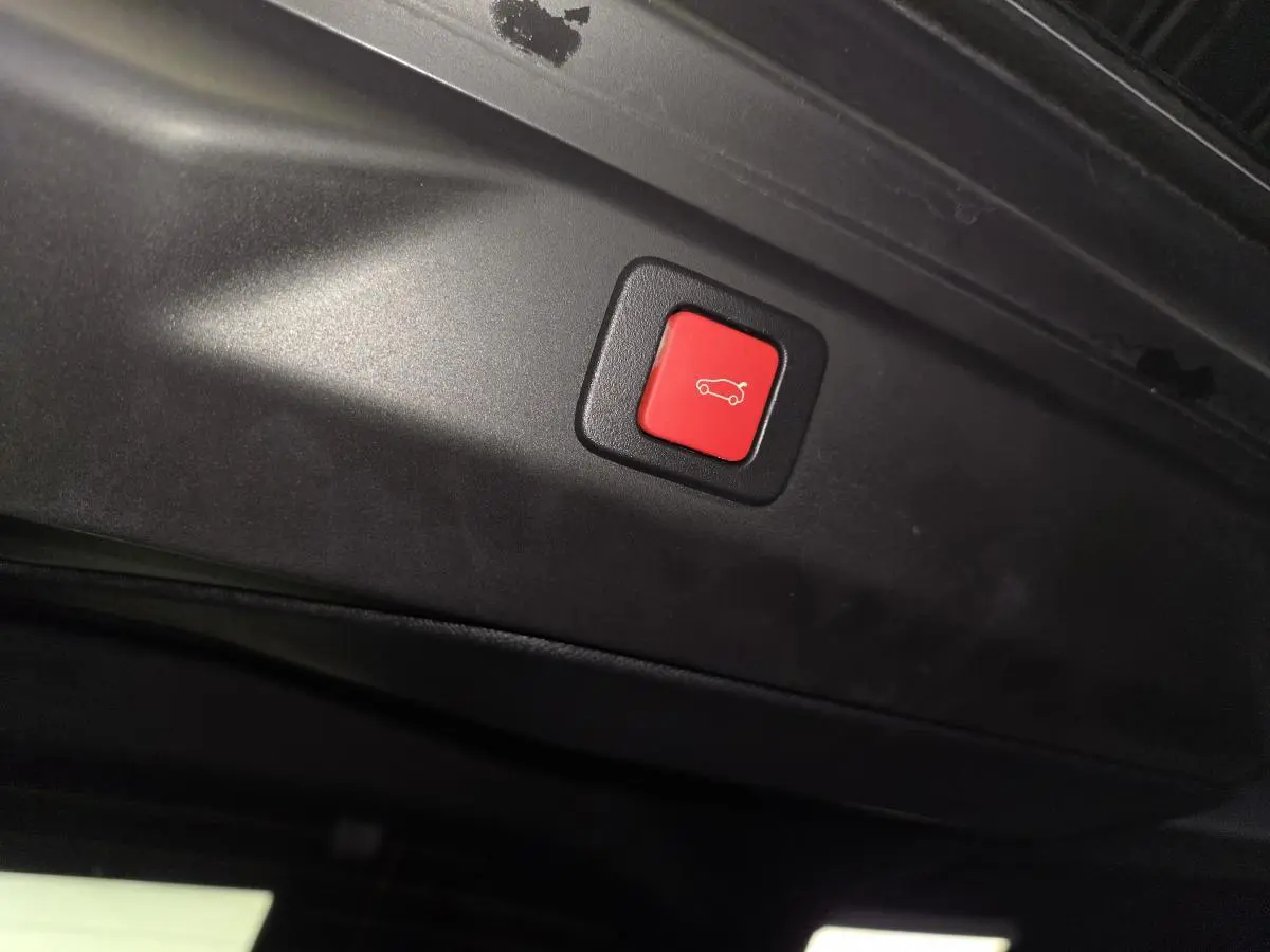 Bouton rouge de fermeture électrique du hayon sur le bord intérieur du coffre du Peugeot 3008 gris 2025.