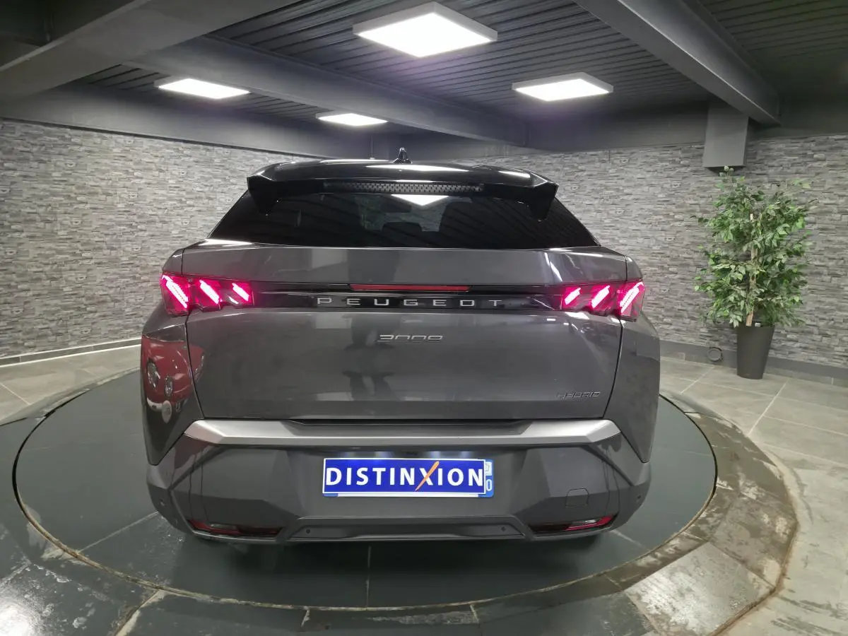 Vue arrière d’un Peugeot 3008 gris métallisé 2025 avec feux arrière LED en forme de griffes et bandeau noir laqué.
