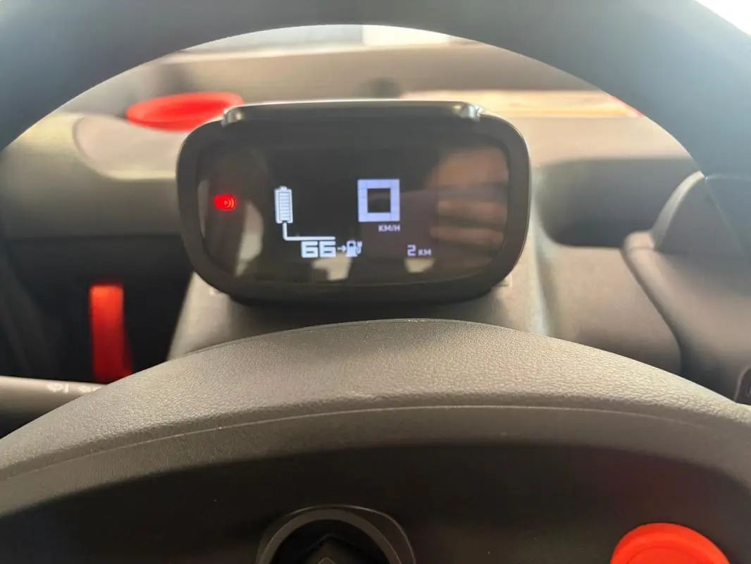 Vue intérieure centrée sur le tableau de bord numérique du Citroën Ami Spicy gris 2025, avec affichage de batterie et compteur.