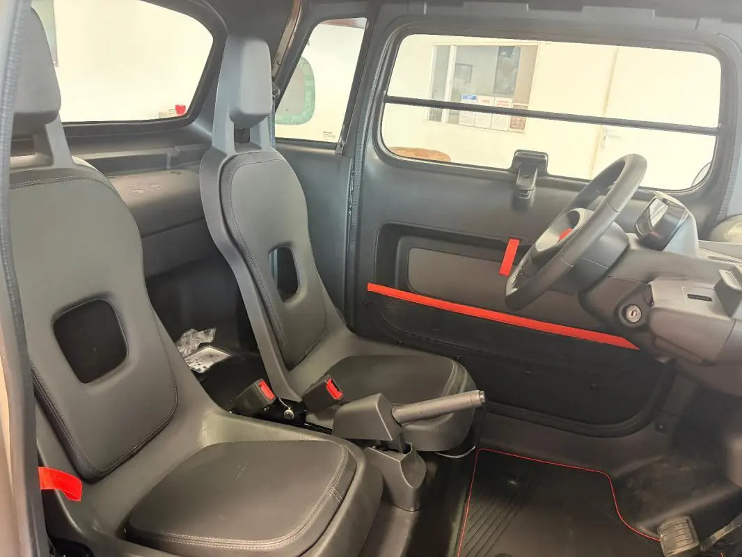 Intérieur de la Citroën Ami Spicy 2025 vu côté droit, sièges gris avec détails rouges et tableau de bord minimaliste.