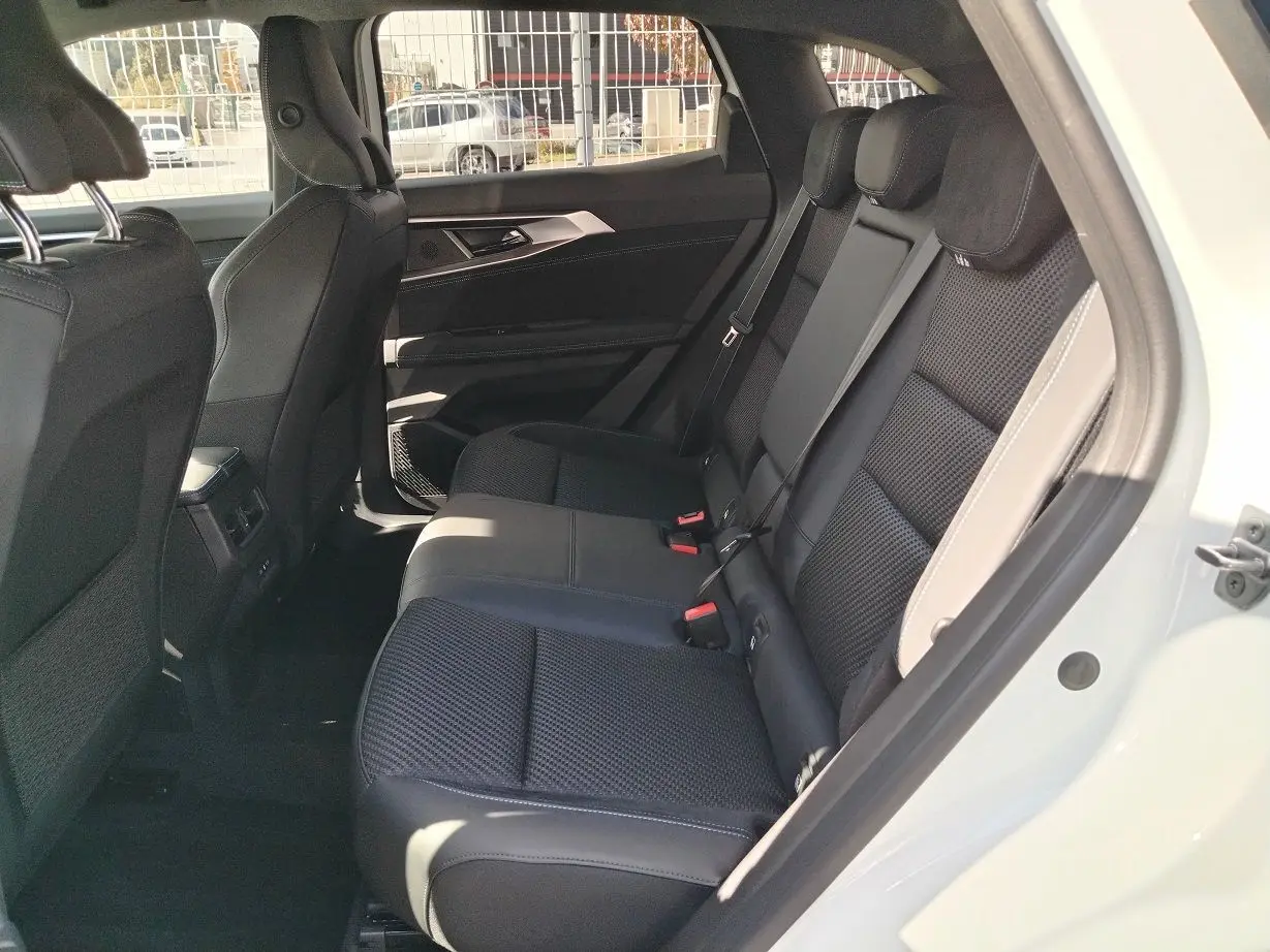 Vue côté droit de l'habitacle arrière du Renault Austral blanc nacré, montrant les sièges noirs en tissu et cuir.