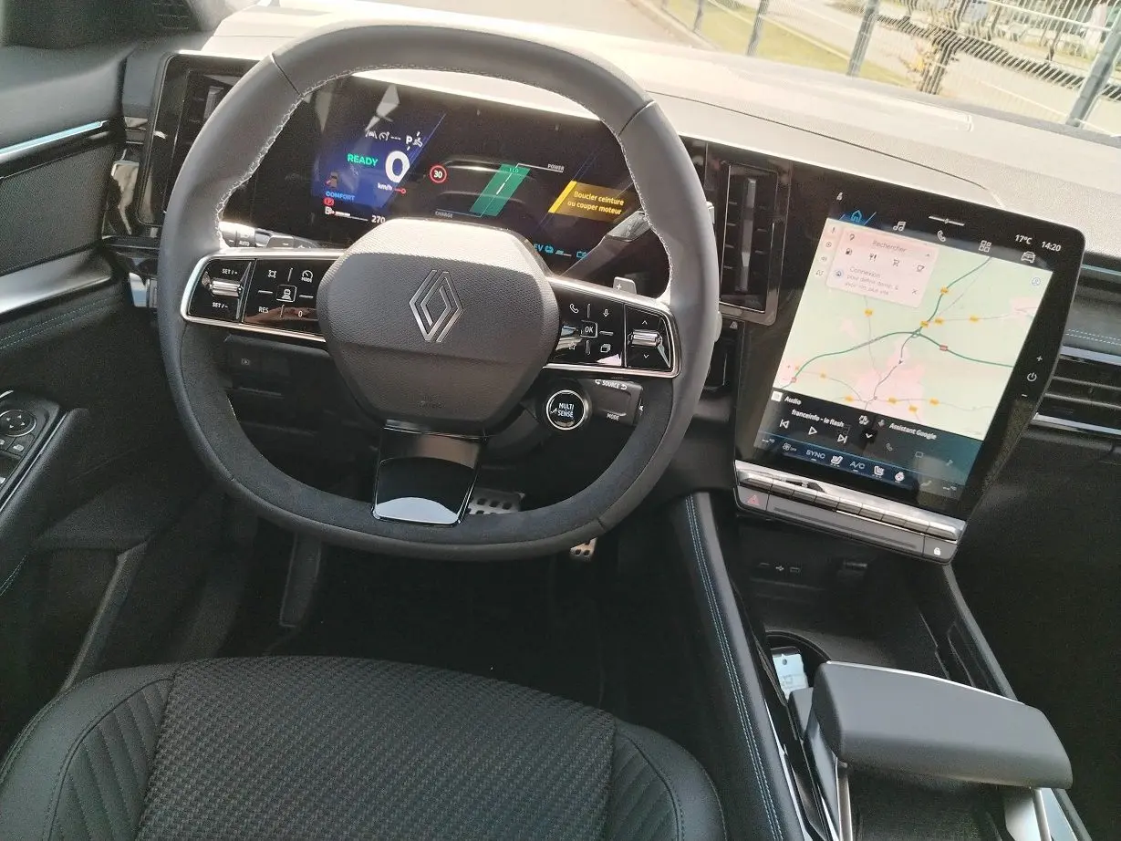 Vue intérieure centrée sur le volant et tableau de bord numérique du Renault Austral E-Tech blanc nacré, avec écran tactile vertical.