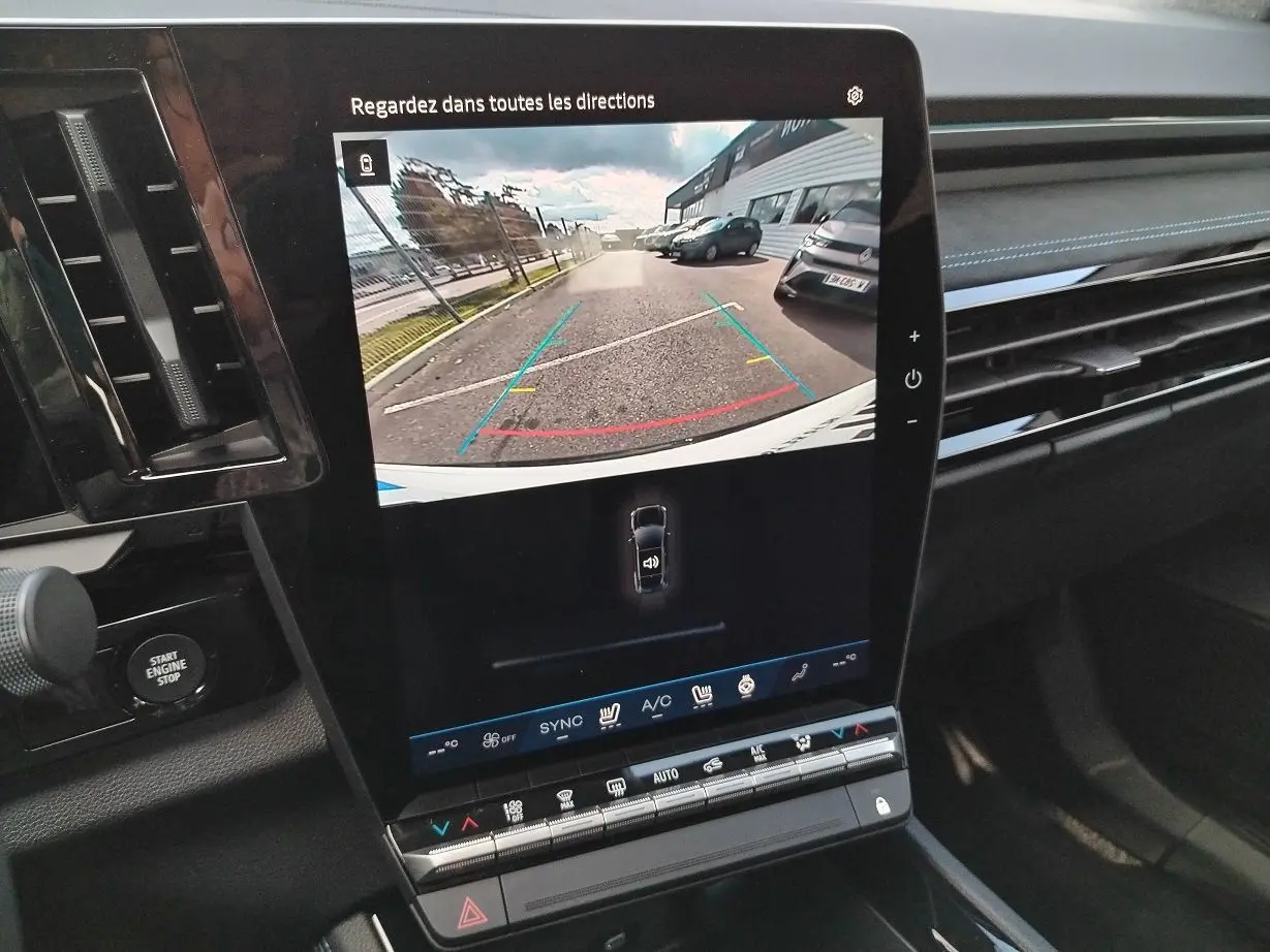 Vue rapprochée de l'écran central tactile du Renault Austral blanc nacré, affichant la caméra de recul avec guidage coloré.