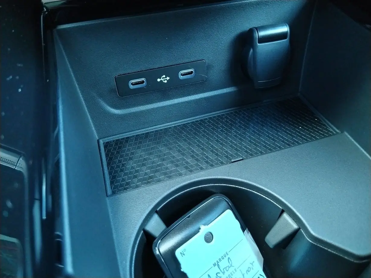 Prise USB double et prise 12V dans la console centrale noire du Renault Austral E-Tech hybride 2025.