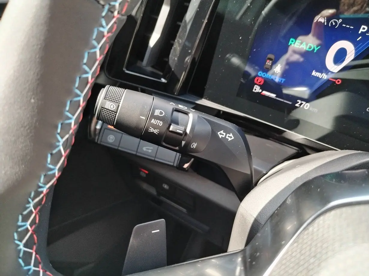 Gros plan sur la manette de clignotant et le tableau de bord digital du Renault Austral blanc nacré 2025.