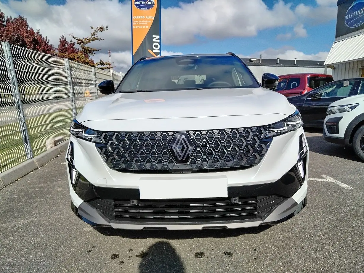 Vue frontale d'un Renault Austral blanc nacré avec toit noir, mettant en valeur sa calandre hexagonale distinctive.