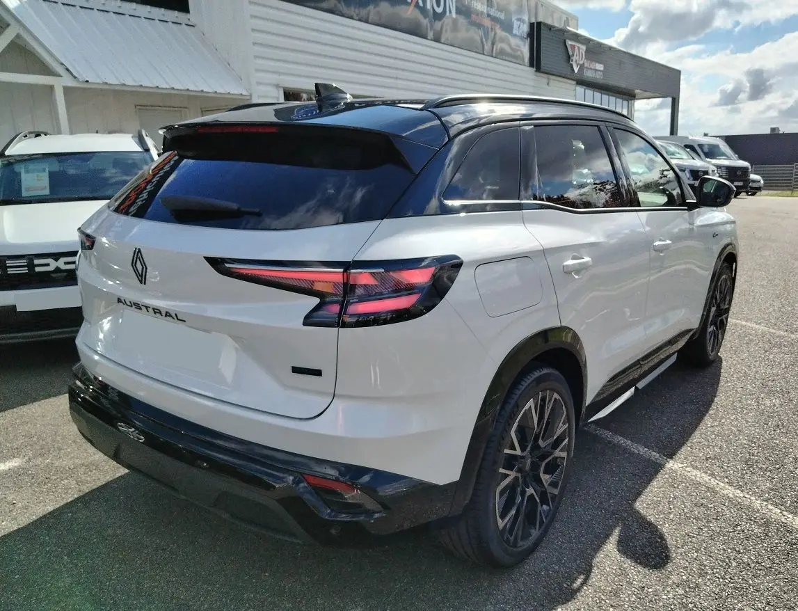 Vue 3/4 arrière droite d'un Renault Austral blanc nacré avec toit noir et jantes noires au design sportif.