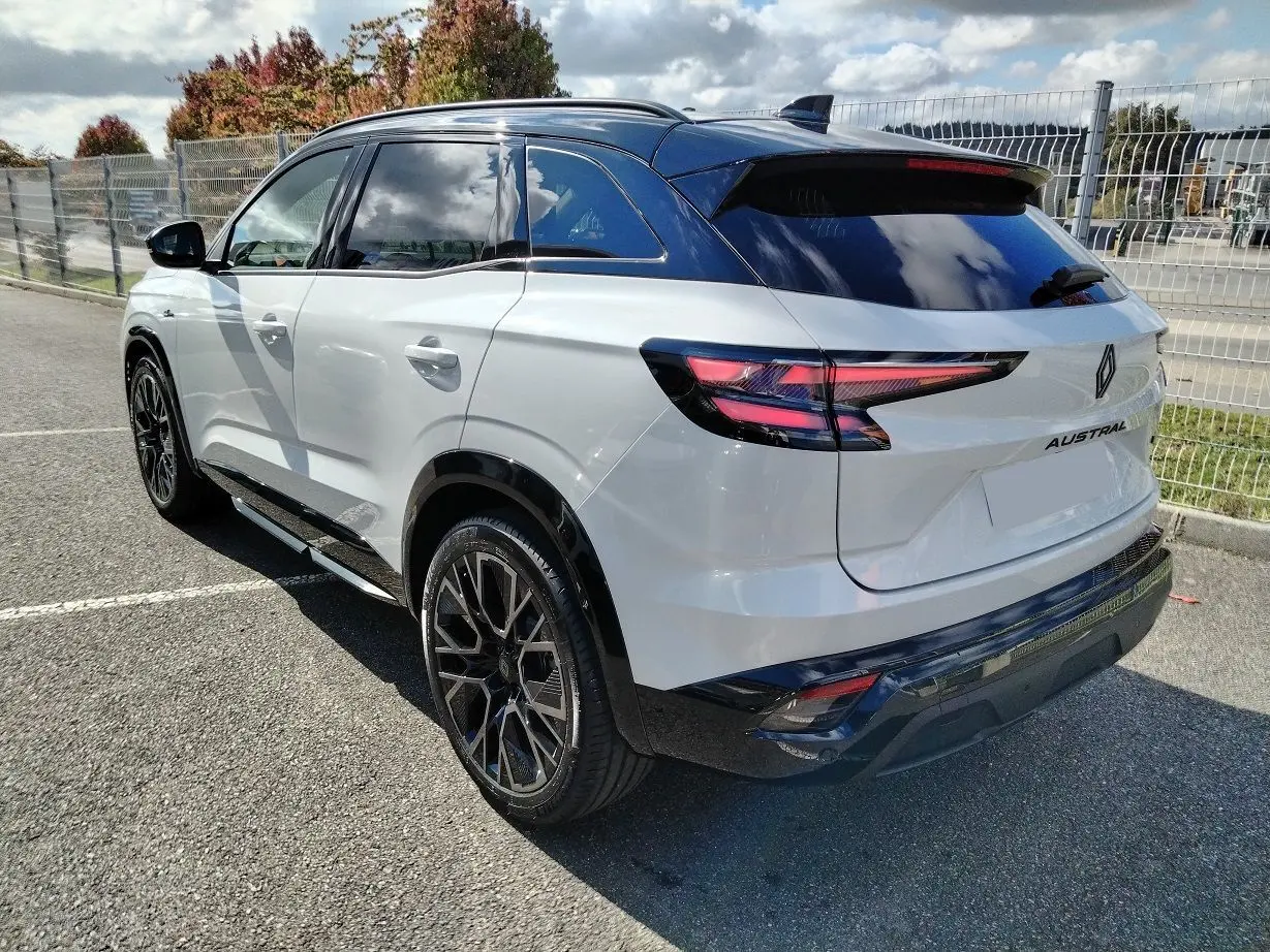 Vue 3/4 arrière droite du Renault Austral blanc nacré avec toit noir et jantes noires distinctives.