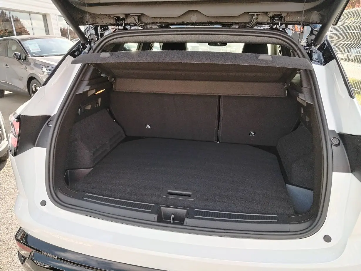 Coffre ouvert vu de l'arrière d'un Renault Austral blanc nacré avec toit noir, montrant un espace de chargement spacieux.