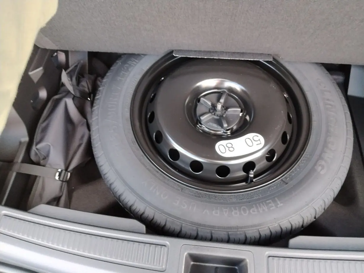 Roue de secours noire en gros plan dans le coffre du Renault Austral E-Tech Full Hybrid 2025 blanc nacré avec toit noir.