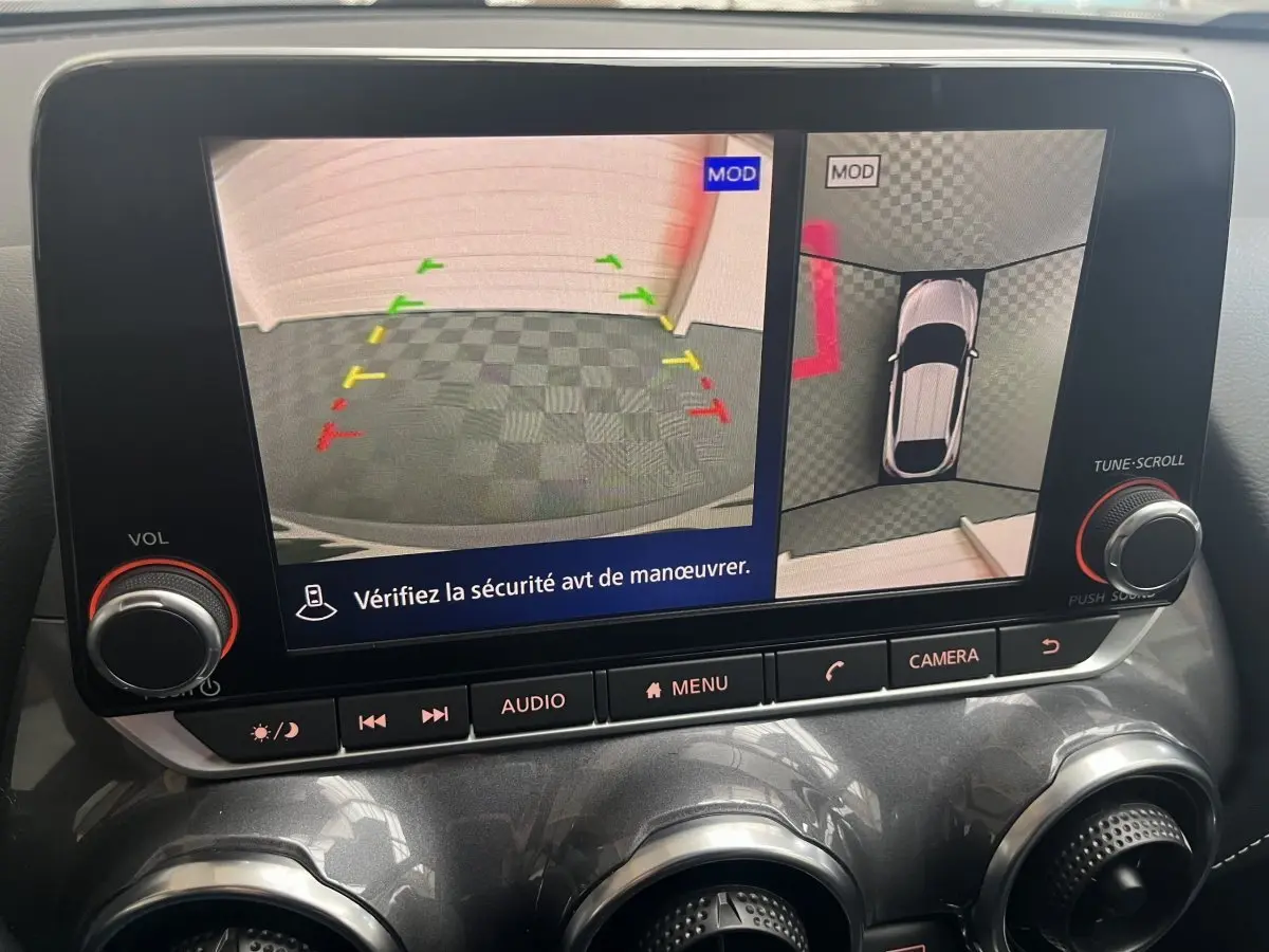Écran tactile intérieur du Nissan Juke Hybrid gris clair 2024 montrant la caméra de recul et vue 360° en stationnement.