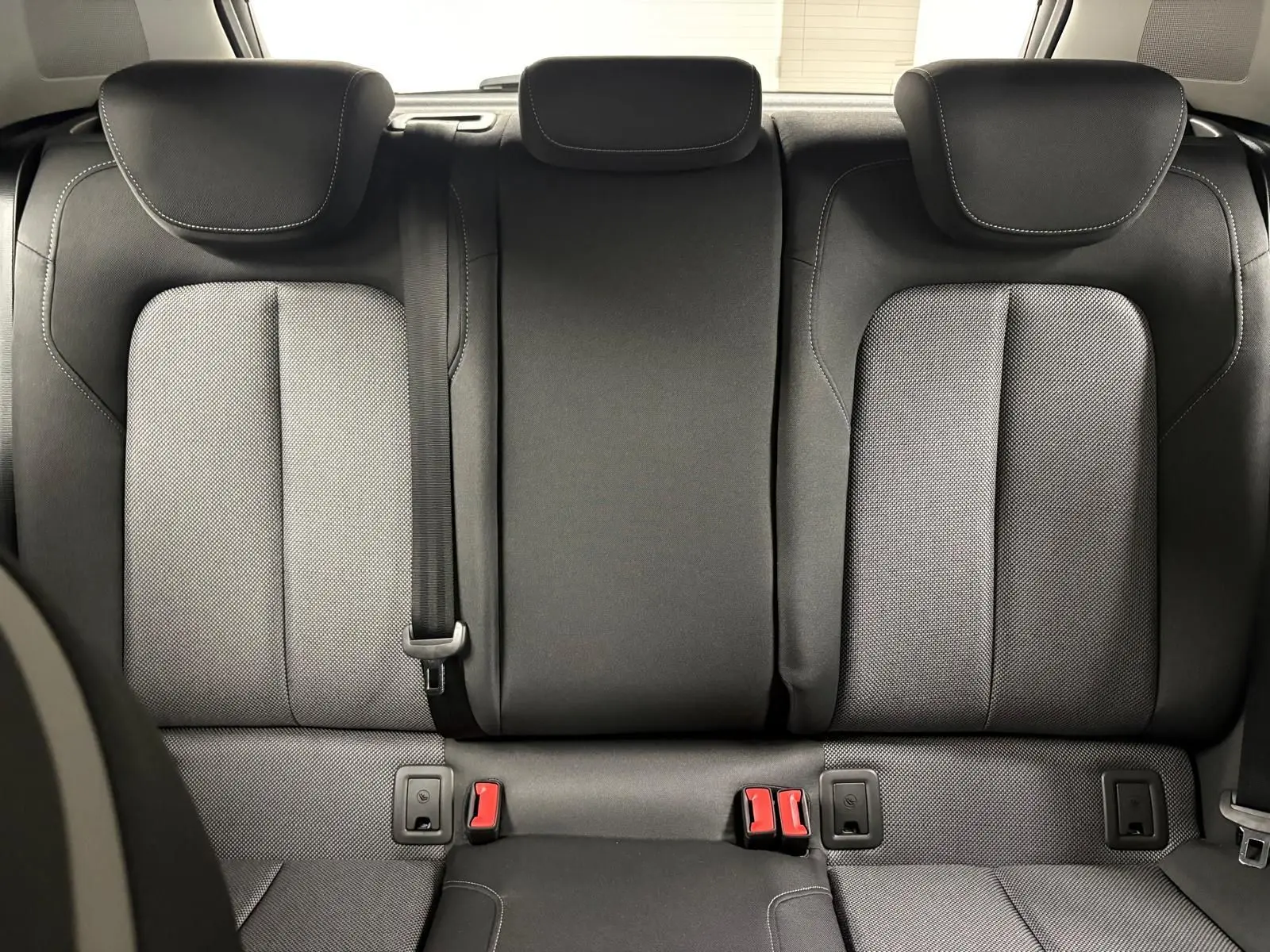 Vue arrière intérieure des sièges arrière noirs de l'Audi Q2 35 TFSI S Line 2026, avec appuie-têtes et ceintures visibles.
