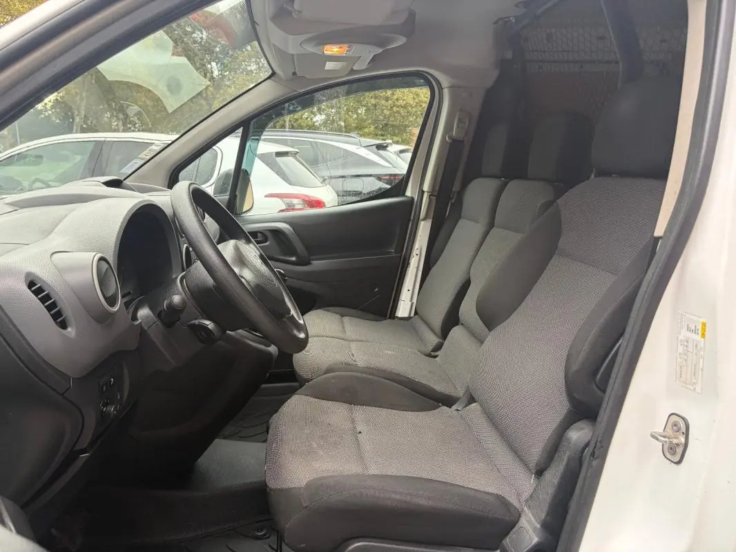 Vue intérieure côté conducteur du Citroën Berlingo blanc 2018, montrant les sièges avant et le tableau de bord simple.