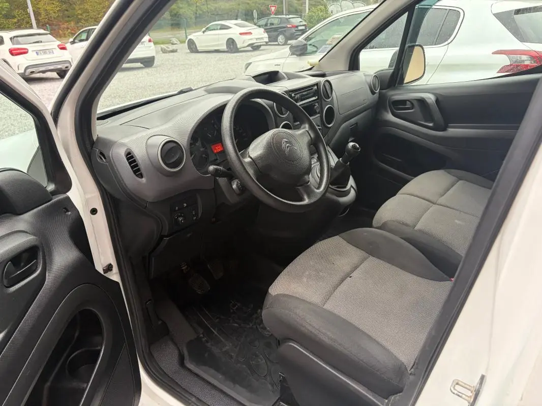 Vue intérieure côté conducteur du Citroën Berlingo blanc 2018, montrant le tableau de bord et les sièges avant gris.