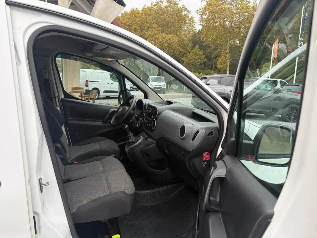 Vue intérieure côté conducteur du Citroën Berlingo blanc 2018, montrant les sièges, le tableau de bord et la boîte manuelle.