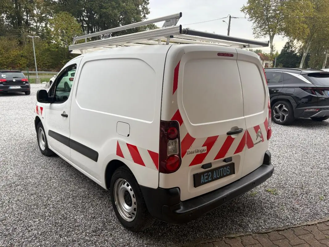 Vue 3/4 arrière droite d’un Citroën Berlingo blanc 2018 avec bandes rouges réfléchissantes et galerie de toit.