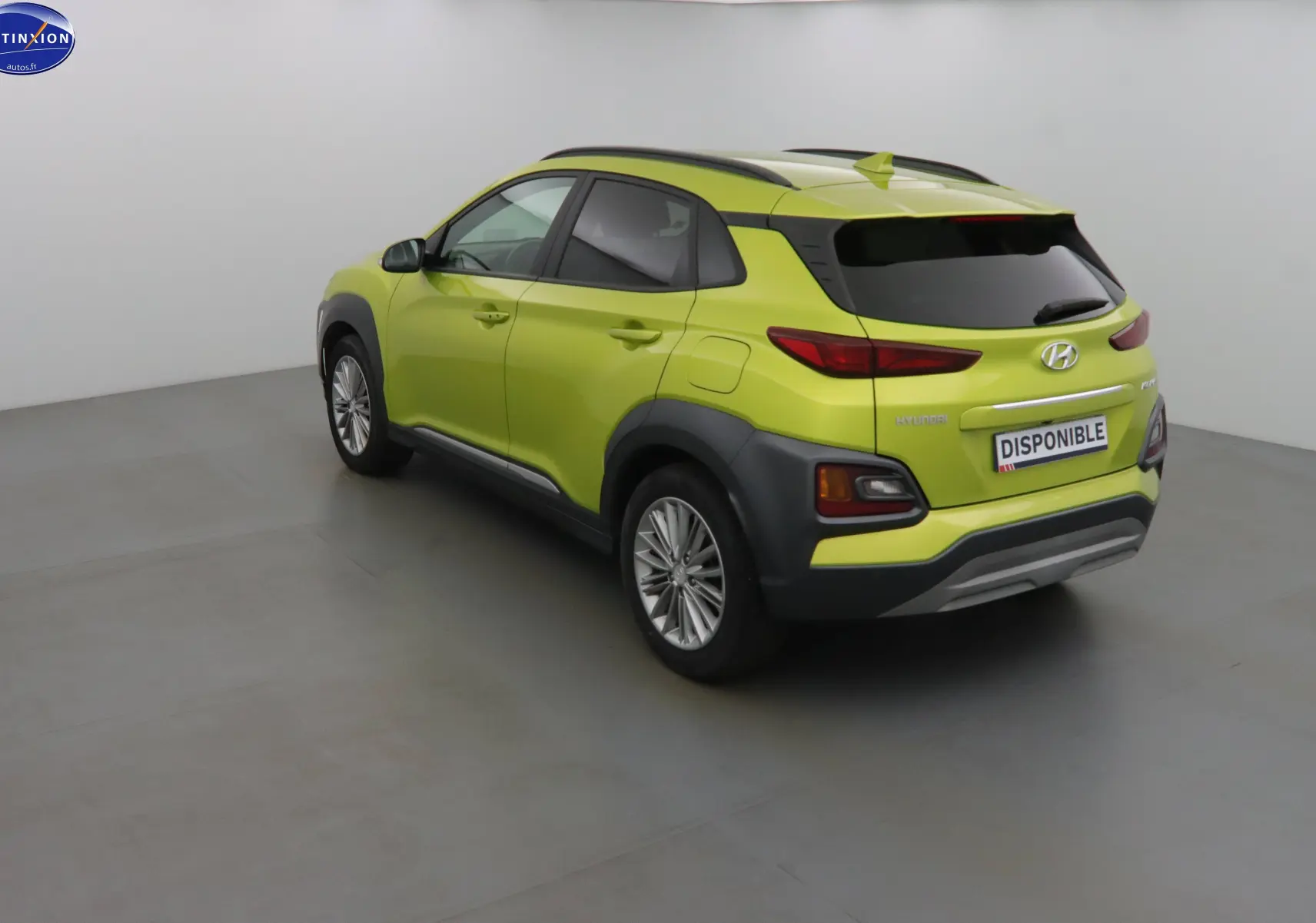 Vue 3/4 arrière droite d'un Hyundai Kona 2019 en jaune acidulé avec protections noires et vitres teintées.