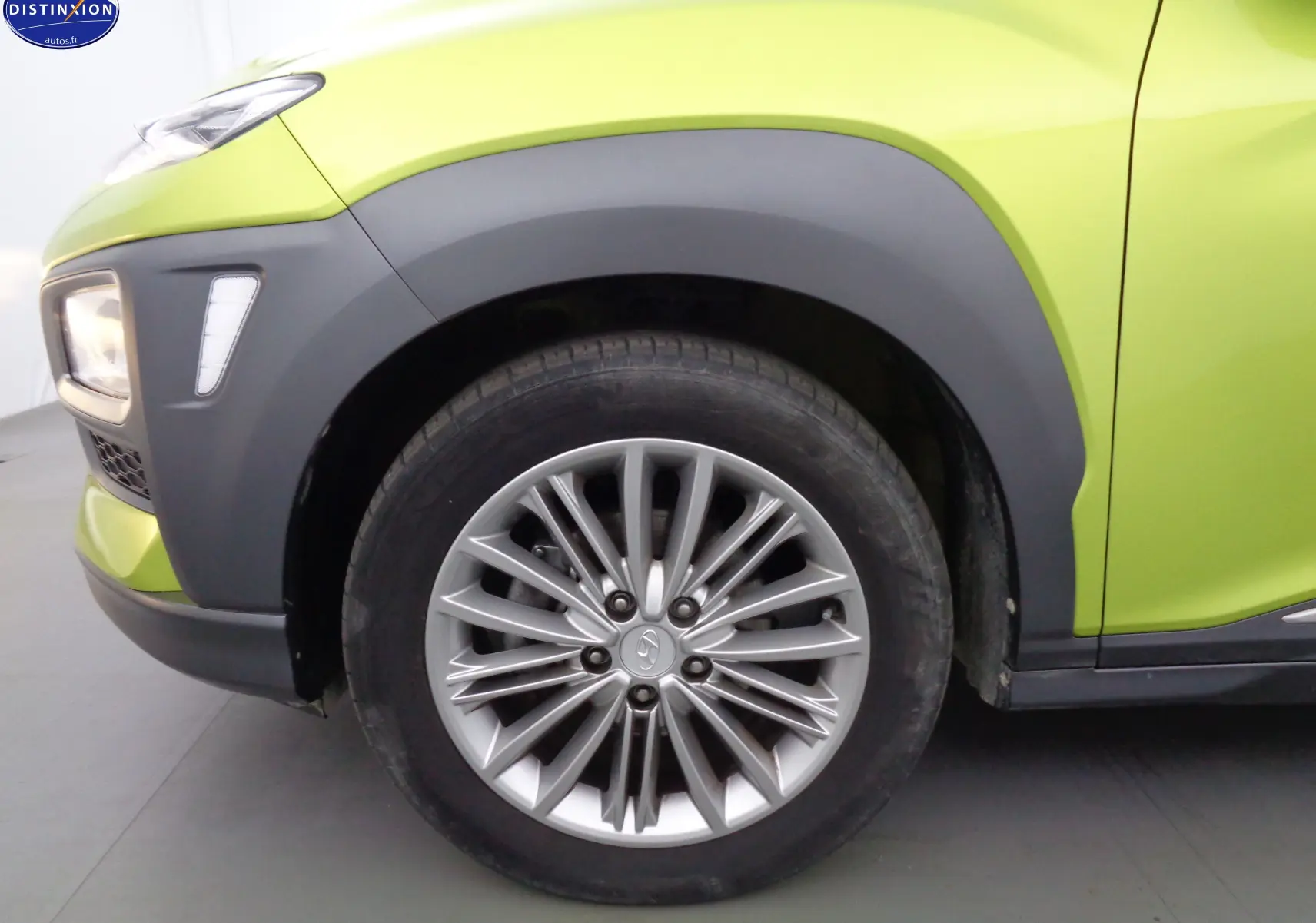 Gros plan sur la roue avant gauche et l'aile d'une Hyundai Kona 2019 jaune acidulé avec protections noires.