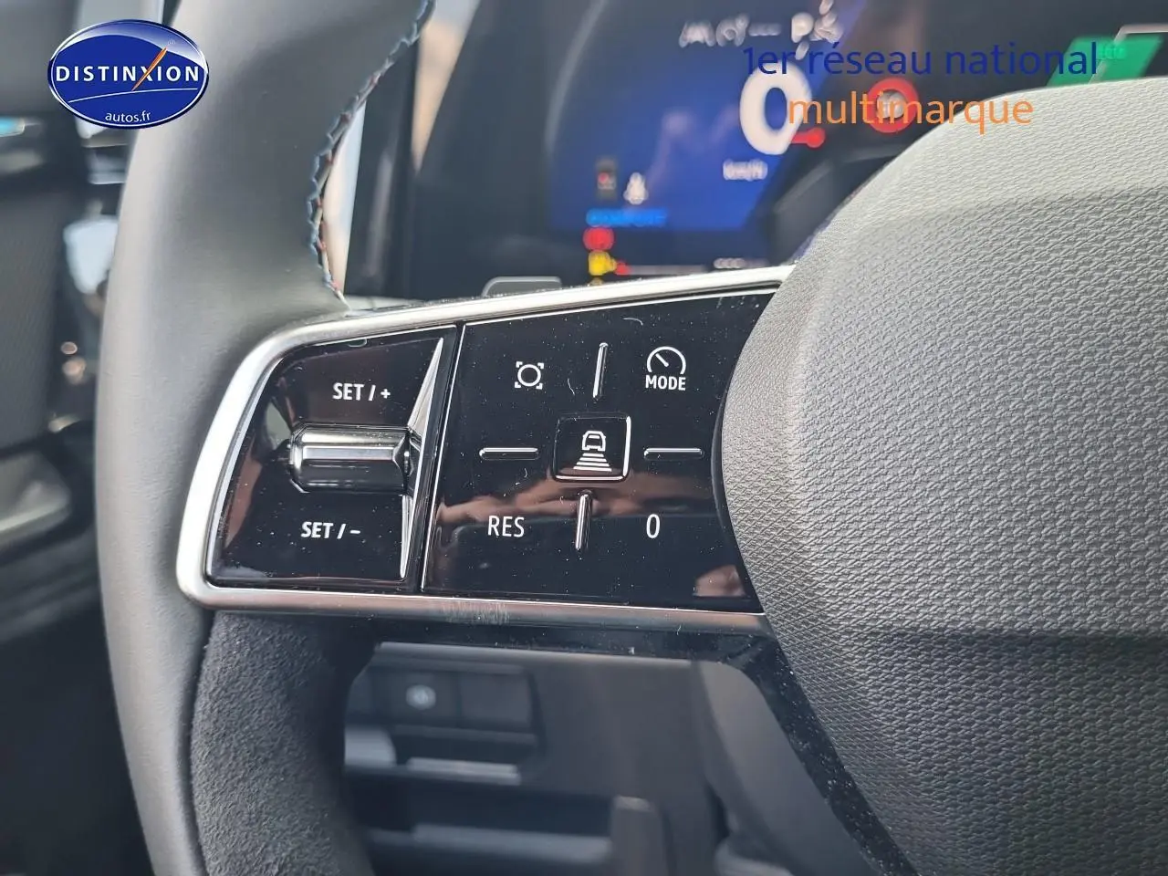 Gros plan sur les commandes multifonctions à gauche du volant du Renault Austral bleu iron, avec affichage numérique en arrière-plan.