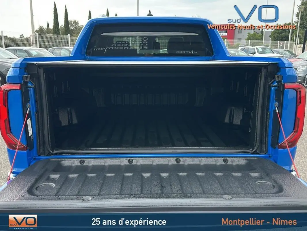 Coffre ouvert en vue arrière d'un Volkswagen Amarok Simple Cabine bleu 2025 avec benne spacieuse et ridelle abaissée.