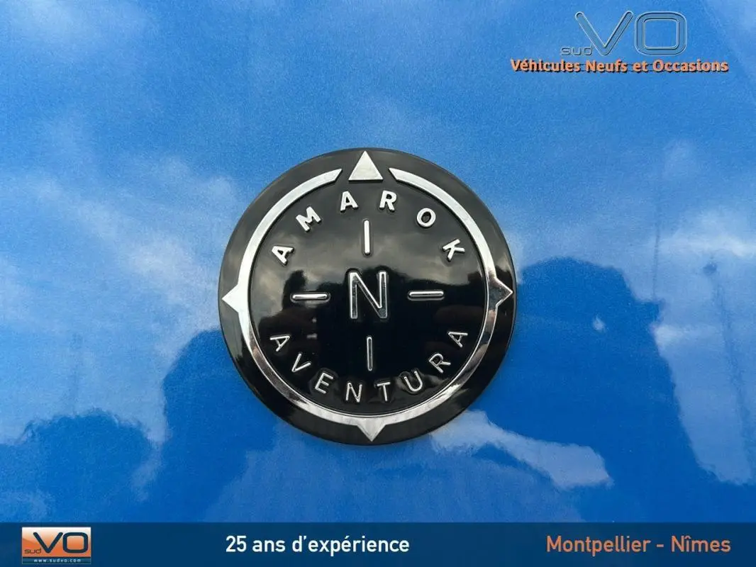 Gros plan sur l'écusson noir et chrome Amarok Aventura sur la carrosserie bleu vif du Volkswagen Amarok 2025.