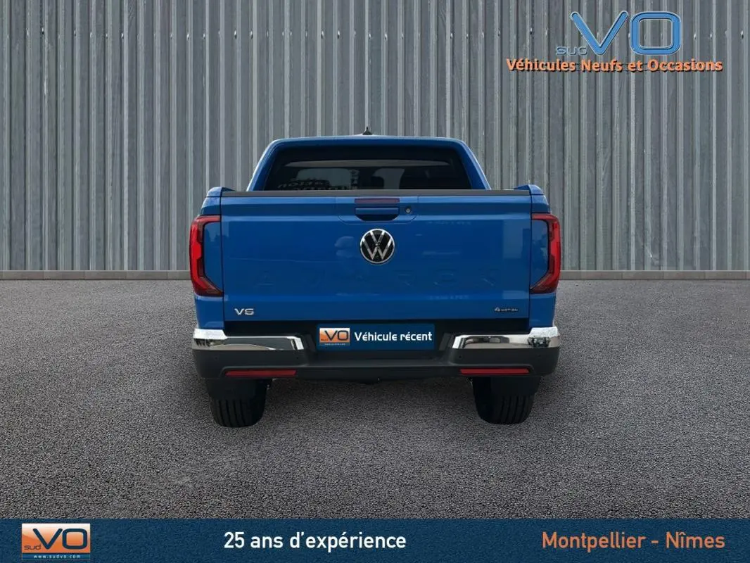 Vue arrière d'un Volkswagen Amarok Simple Cabine bleu 2025 avec logo VW et feux rouges verticaux visibles.
