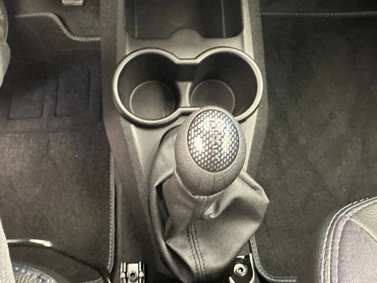 Gros plan sur le levier de vitesses automatique et porte-gobelets au centre de l’habitacle d’une Aixam Ambition blanche.