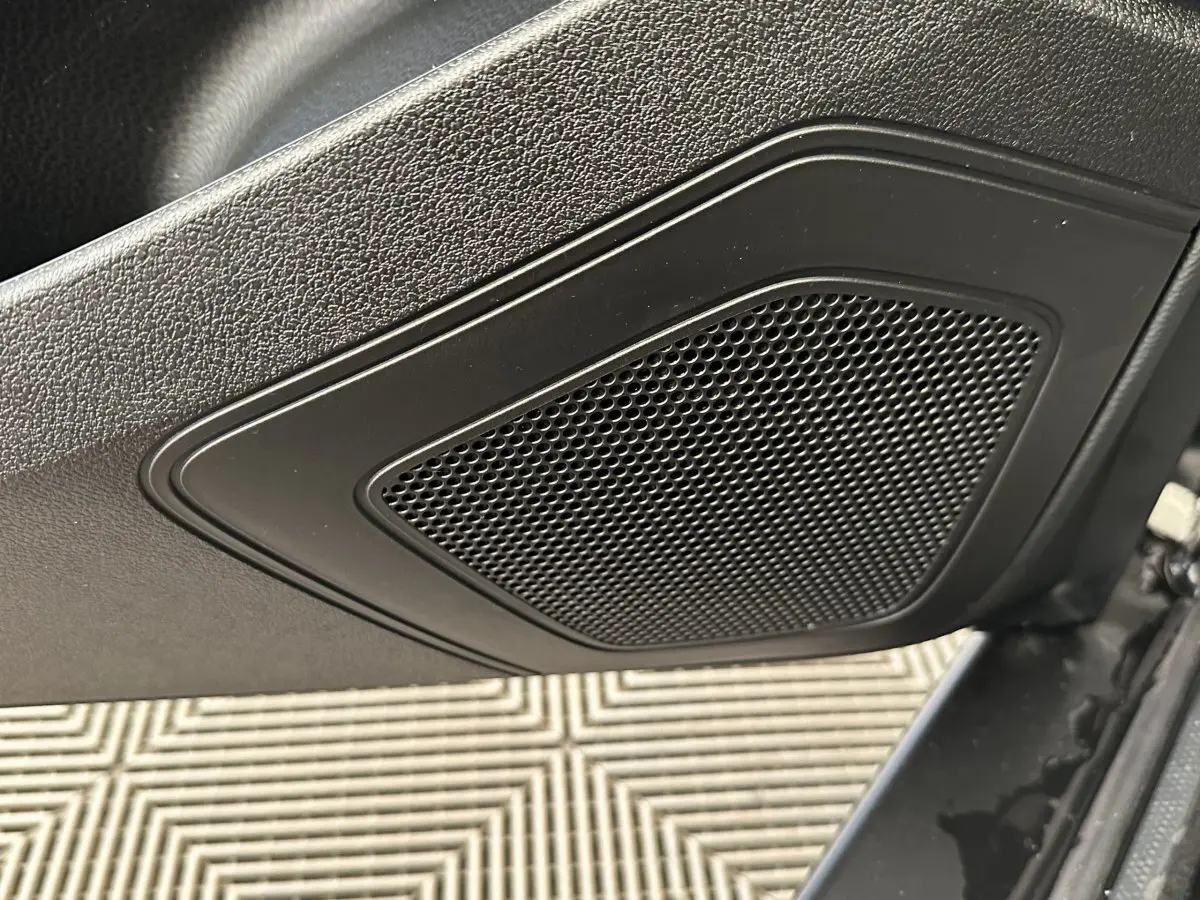 Gros plan sur le haut de la porte côté conducteur de l'AIXAM AMBITION blanc, mettant en valeur le haut-parleur intégré.