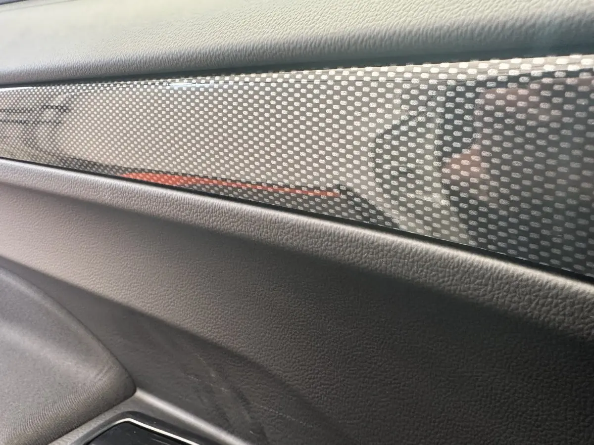Détail intérieur montrant la garniture en carbone et le revêtement noir de la porte côté conducteur de l'AIXAM AMBITION 0.5 CITY GTO.