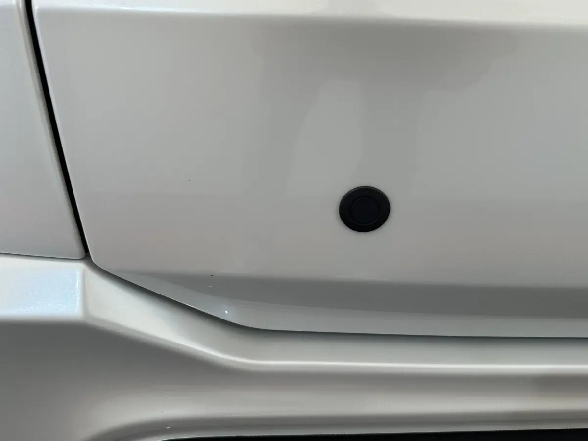 Détail du pare-chocs blanc de l'AIXAM AMBITION 0.5 CITY GTO 2026 avec capteur de stationnement noir.