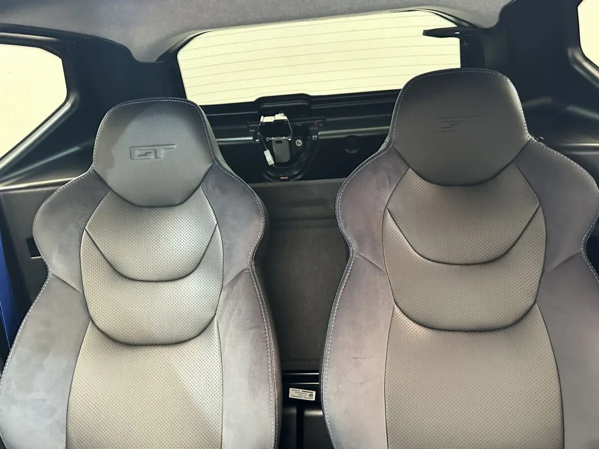 Vue intérieure sur les sièges avant gris avec logo GT, arrière noir et partie vitrée du toit visible.