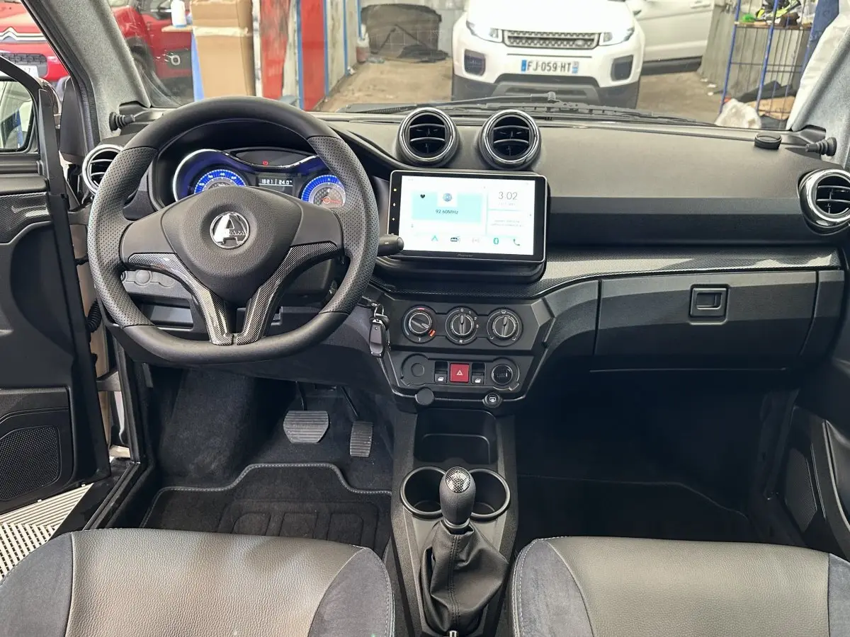 Vue intérieure frontale de l'AIXAM AMBITION 0.5 CITY GTO 2026 avec tableau de bord noir et écran tactile central.