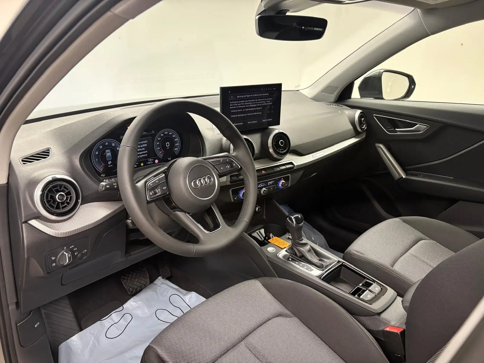 Vue intérieure côté conducteur de l'Audi Q2 35 TFSI S Line 2026, avec tableau de bord moderne et sièges tissu gris.