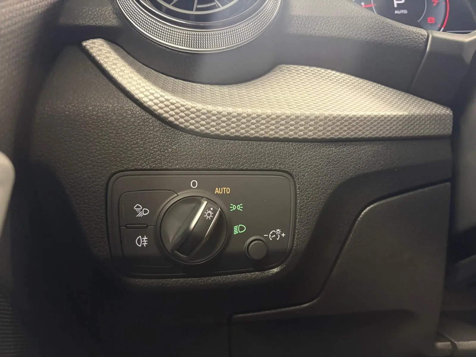 Gros plan sur la commande des phares à gauche du volant dans l’Audi Q2 35 TFSI 150 S Line gris Daytona 2026.
