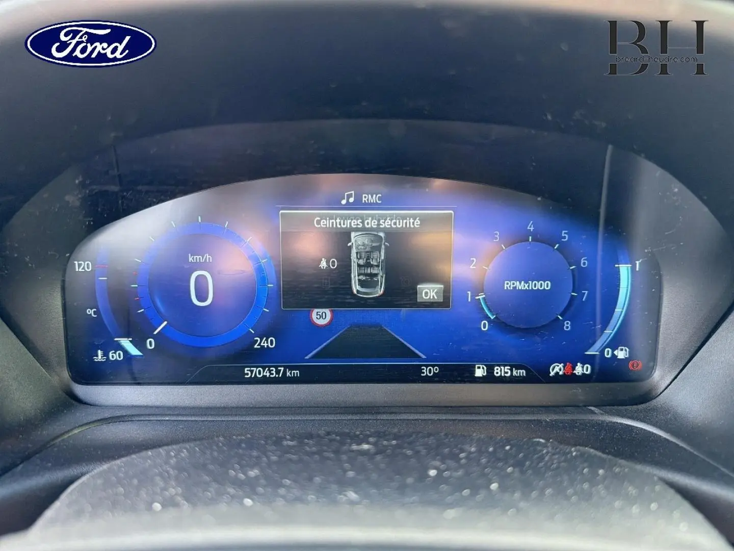Gros plan sur le tableau de bord numérique bleu du Ford Puma 2024, affichant vitesse, compte-tours et alertes sécurité.
