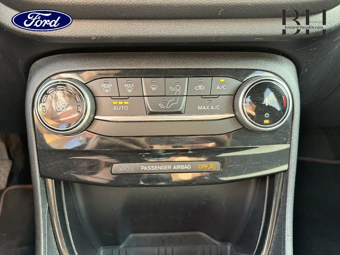 Gros plan sur la console centrale du Ford Puma 2024 gris Solar, montrant les commandes de climatisation et l'indicateur airbag passager.