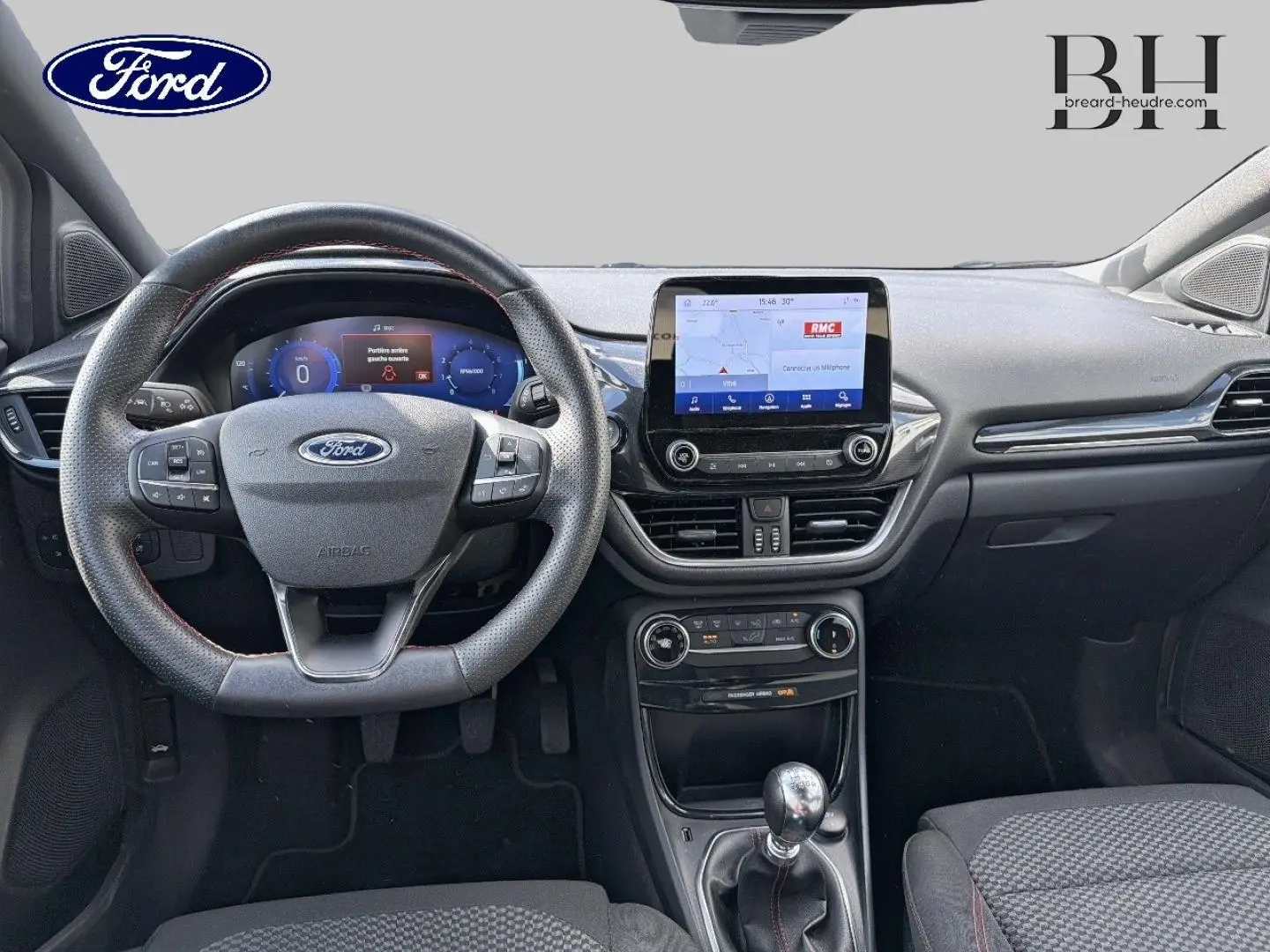 Vue intérieure frontale du tableau de bord du Ford Puma 2024 avec volant multifonction, écran tactile central et levier de vitesses manuel.