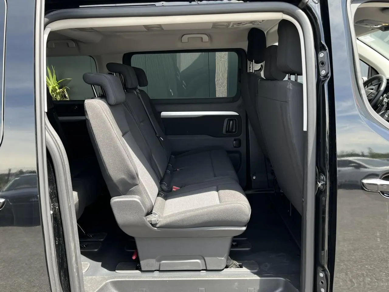 Vue latérale intérieure du Citroën Spacetourer XL noir Perla, montrant les sièges passagers en tissu gris et portes latérales ouvertes.