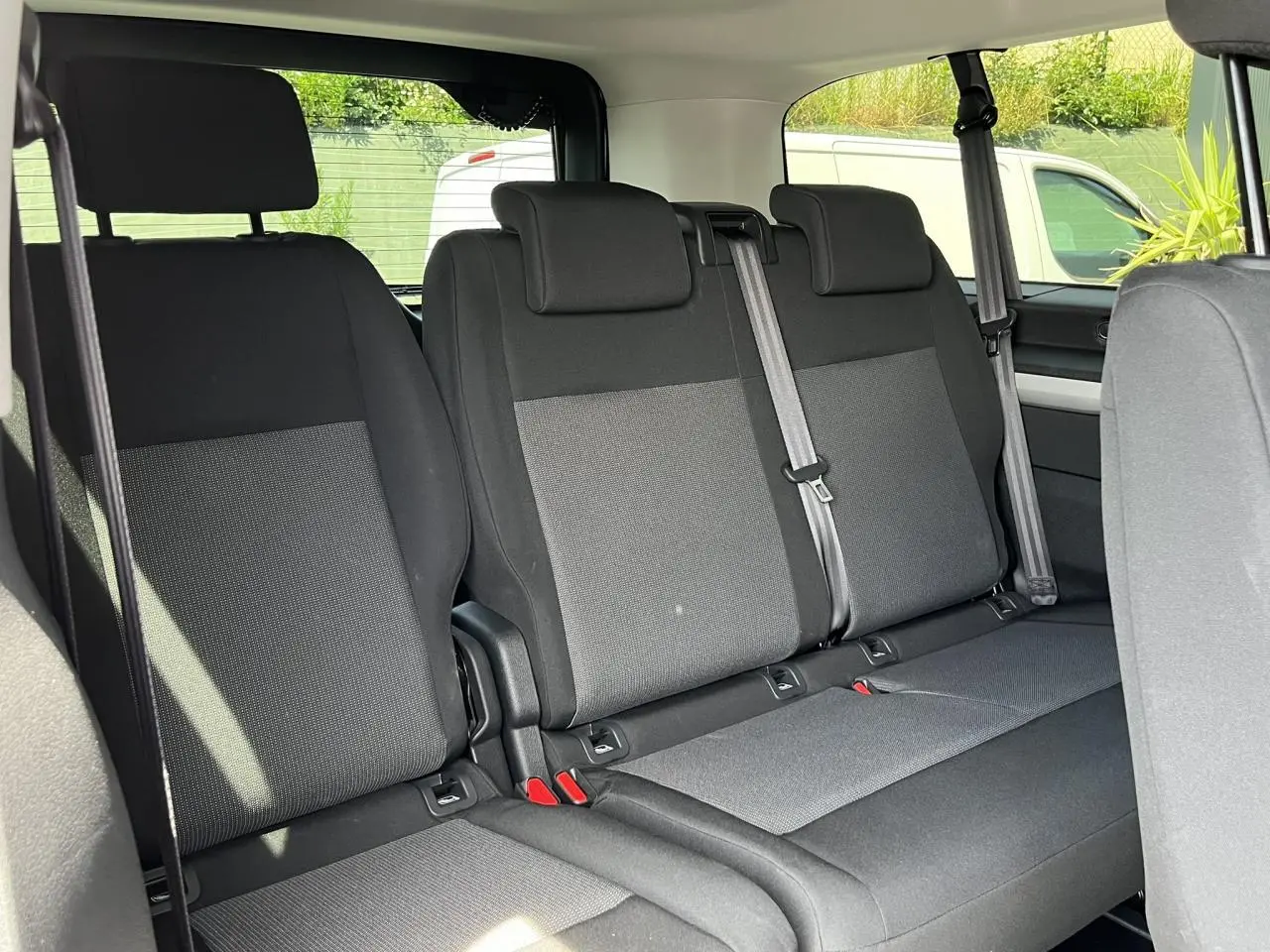 Vue intérieure montrant la banquette arrière en tissu gris et noir du Citroën Spacetourer XL 2024 avec ceintures de sécurité visibles.