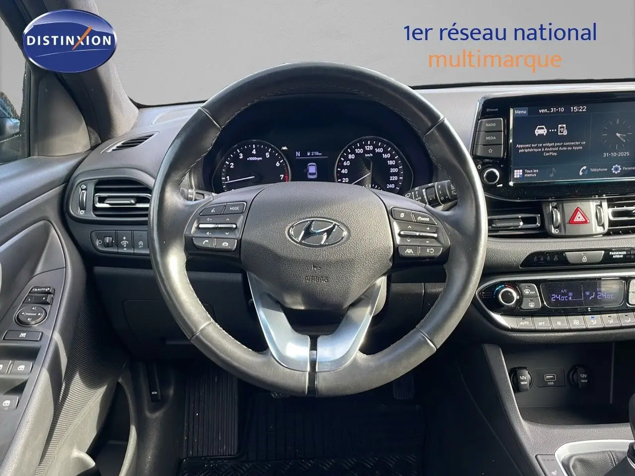 Vue intérieure centrée sur le volant et tableau de bord de la Hyundai i30 SW 2024, finition PLAY, avec écran tactile et commandes au volant.