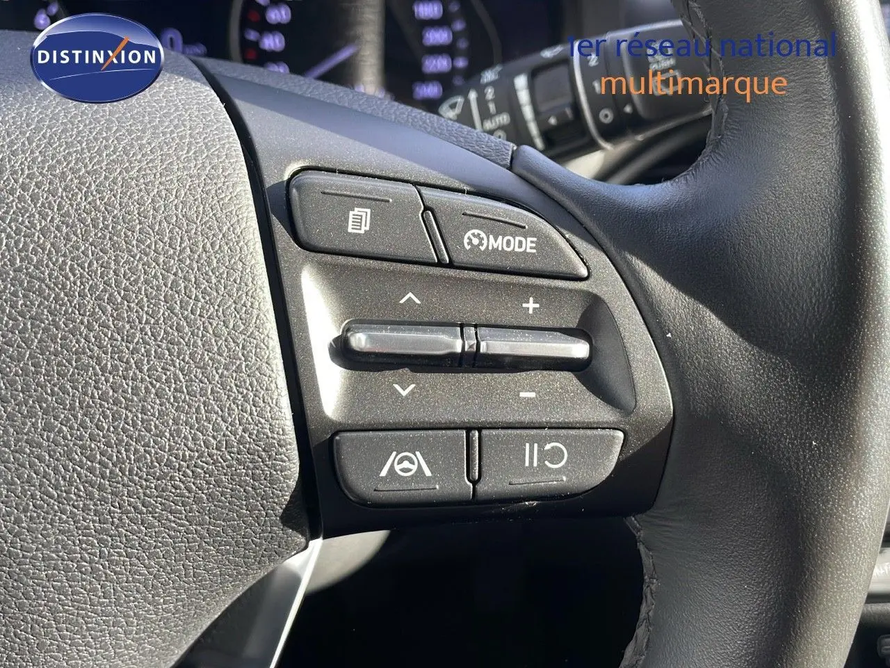 Gros plan sur les commandes au volant à droite d'une Hyundai i30 SW 2024 couleur Dark Knight Metal, avec boutons mode et régulateur.