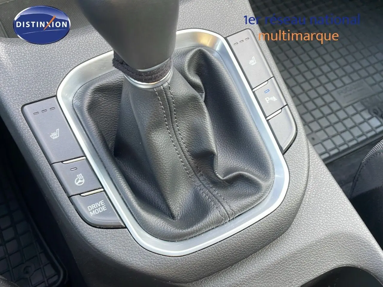 Gros plan sur la console centrale de la Hyundai i30 SW 2024, levier de vitesse manuel en cuir noir et boutons chauffants.