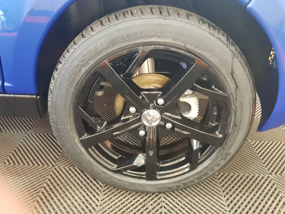 Gros plan sur la roue avant droite noire brillante d'une Aixam Ambition 0.5 City Sport bleu 2026.