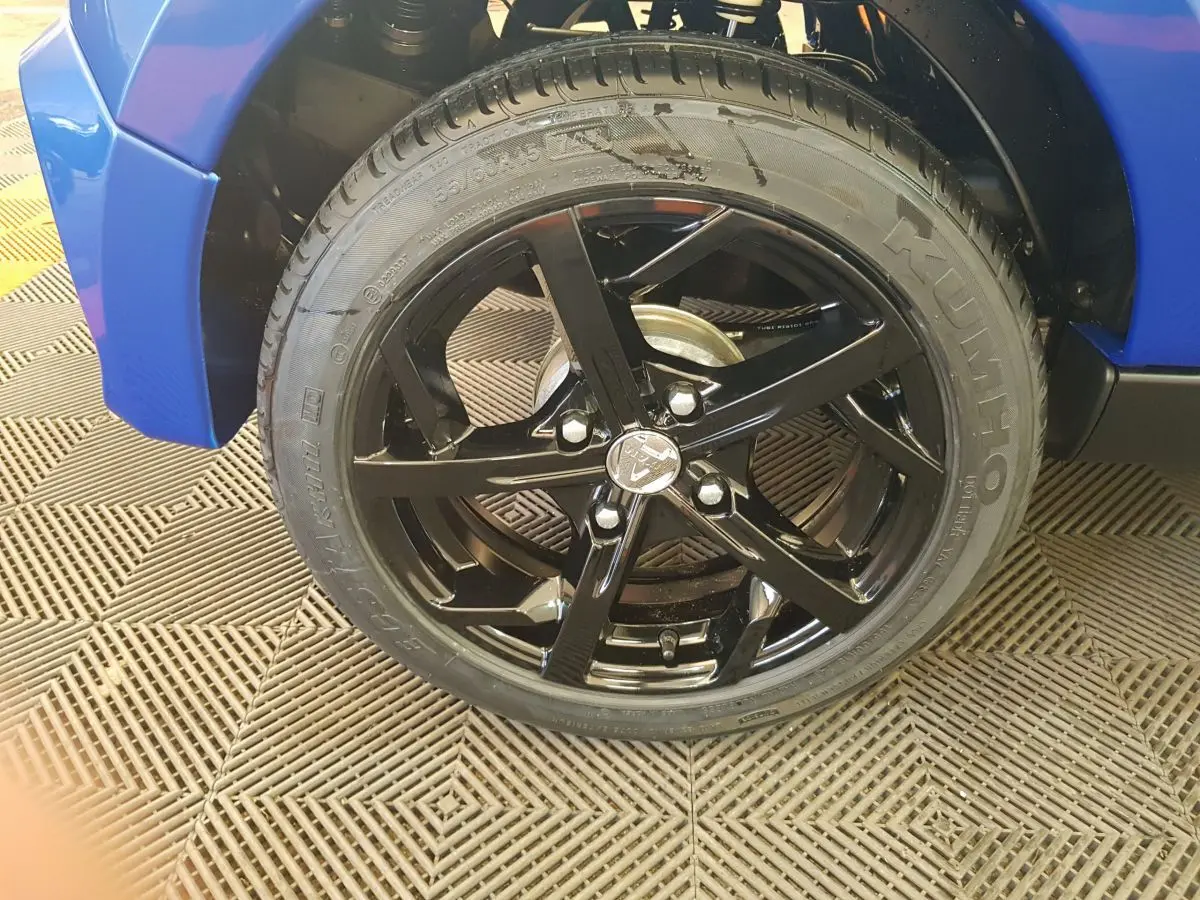 Gros plan sur la roue avant droite noire brillante de l'AIXAM AMBITION 0.5 CITY SPORT bleu 2026.