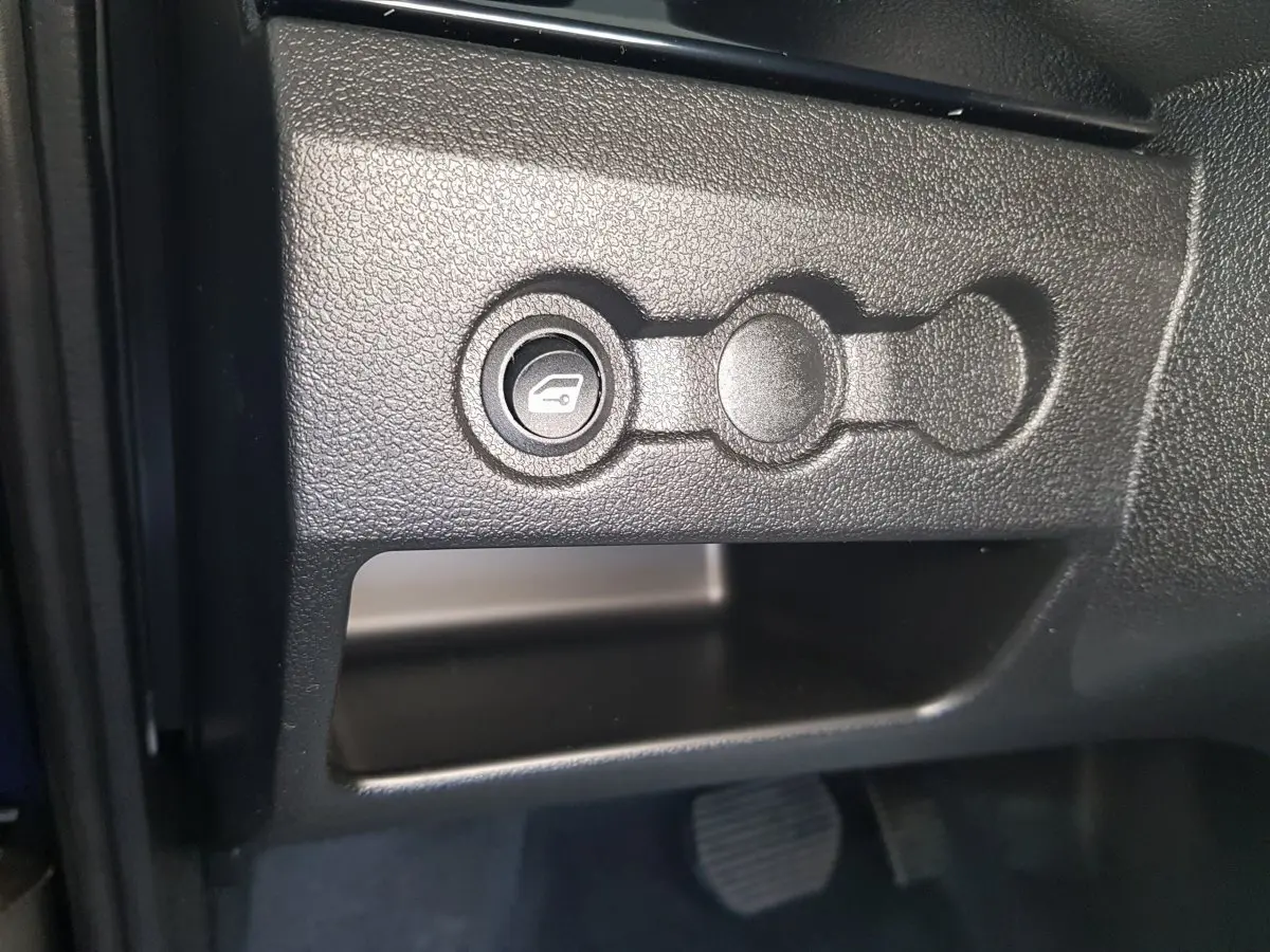 Gros plan sur le bouton d'ouverture du coffre dans l'habitacle de l'AIXAM AMBITION 0.5 CITY SPORT 2026 bleu.