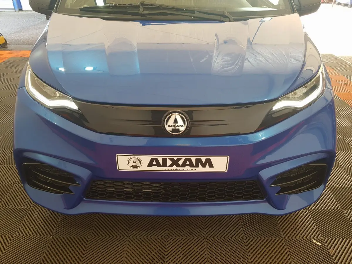 Vue frontale d'une Aixam Ambition 0.5 City Sport bleu avec calandre noire et phares LED allumés.