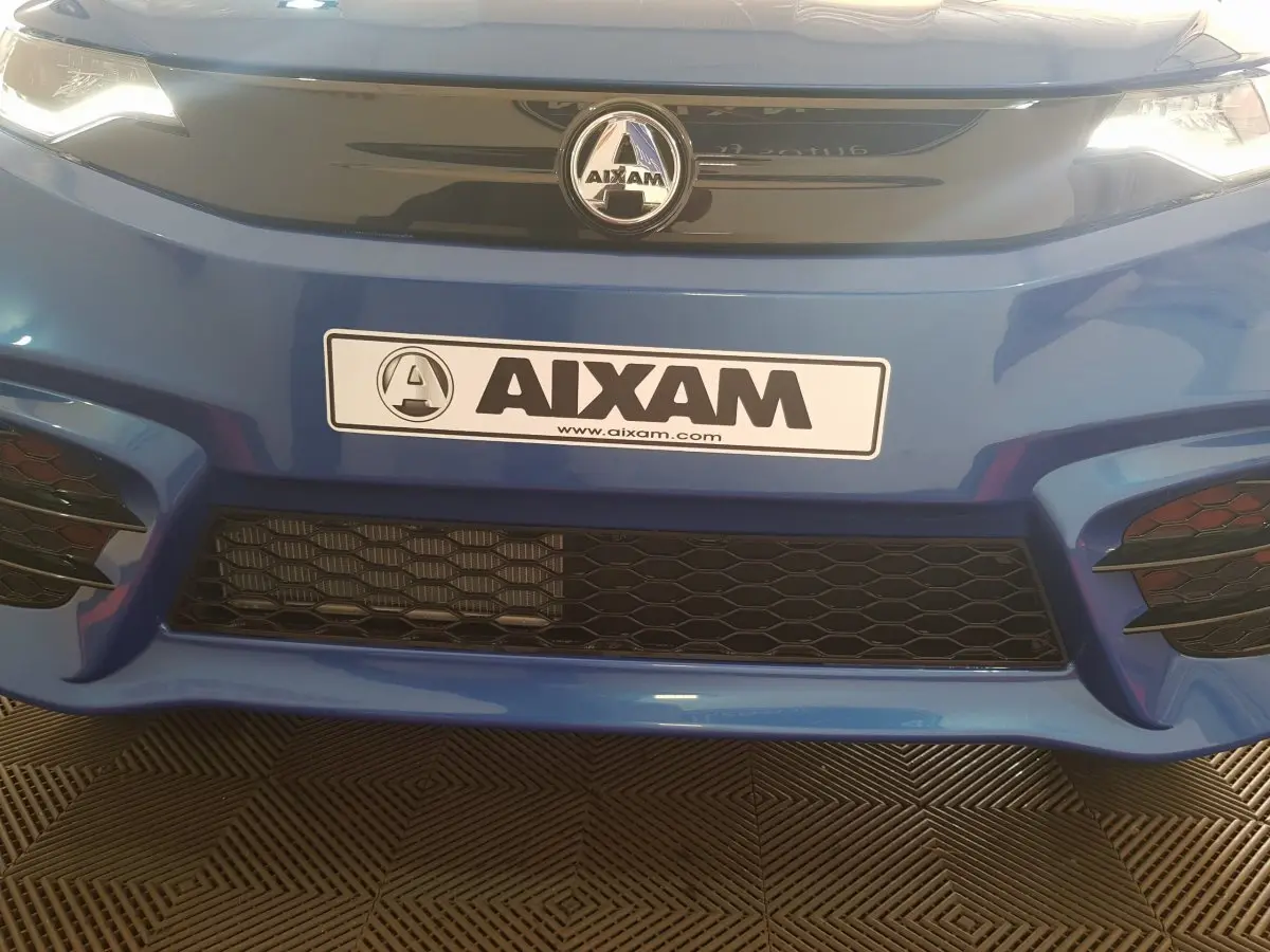 Gros plan sur la calandre avant bleue de l'AIXAM AMBITION 0.5 CITY SPORT avec logo et plaque AIXAM visible.