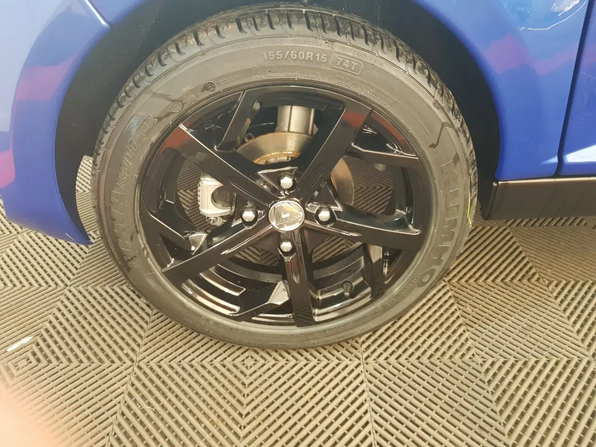 Gros plan sur la roue avant droite noire brillante d'une Aixam Ambition 0.5 City Sport bleu 2026.