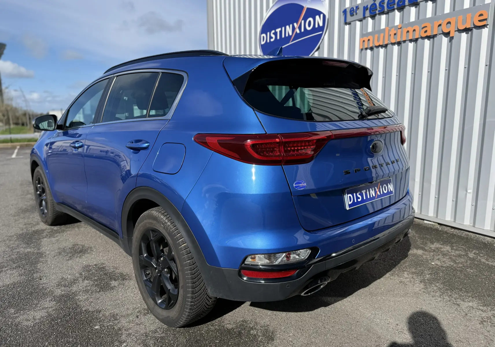 Vue 3/4 arrière droite du KIA SPORTAGE 1.6 CRDI 136 Black Edition bleu avec jantes noires et feux arrière LED.
