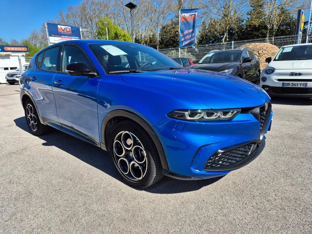 Vue 3/4 avant gauche d'une Alfa Romeo Tonale 1.5 Hybrid bleu 2025 avec jantes alliage 18 pouces et rétroviseurs noirs.